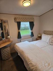 a bedroom with a large bed and a window at KMH Caravans at Flamingo Land in Kirby Misperton