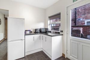 ベッドフォードにあるLuxeVille I Serene 3BR Apartment with Private Courtyard I LongTerm RatesI ParkingI WiFiの白いキャビネットと窓のあるキッチン