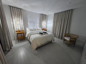 a white bedroom with a bed and a chair at Yzer Heights Relaxed Luxury Stay in Yzerfontein +13 photos