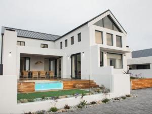 a white house with a swimming pool and a patio at Yzer Heights Relaxed Luxury Stay in Yzerfontein