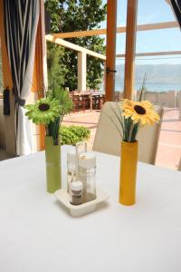 a table with two vases with flowers and candles on it at Rooms by the sea Metajna, Pag - 3305 in Zubovići