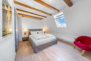 a bedroom with a bed and a red chair at Lighthouse 2 in Hörnum