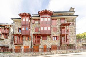 een oud stenen gebouw met rode ramen en balkons bij A Cozy Refuge - 2min drive to slopes - 4pax in Soldeu