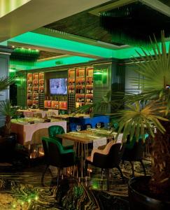 een restaurant met tafels en stoelen en groene verlichting bij Central Address 4 - Palace of Parliament Area in Boekarest