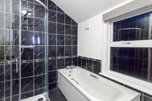 ベッドフォードにあるLuxeVille I Serene 3BR Apartment with Private Courtyard I LongTerm RatesI ParkingI WiFiのバスタブと窓のあるバスルーム +8枚の写真