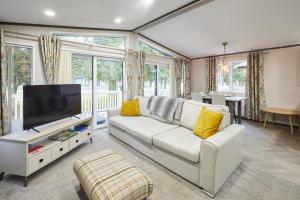 Il comprend un salon doté d'un canapé blanc et d'une télévision à écran plat. dans l'établissement Brackencroft Lodge with Hot Tub, à York