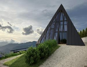 a large glass building on a hill with mountains in the background at Emshir Villas in Krasnik
