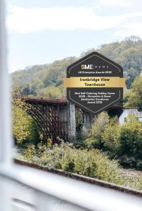 a sign for a bridge over a river at Ironbridge View Townhouse WINNER 2025 UK MOST PICTURESQUE SELF-CATERING HOLIDAY HOME & WINNER SELF-CATERING ACCOMMODATION OF THE YEAR 2025 in Ironbridge