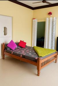 a bed with colorful pillows on it in a room at Gardenia Inn in Madikeri