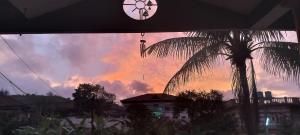 a sunset with a clock and a palm tree at Gardenia Inn in Madikeri