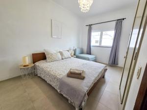 een slaapkamer met een bed, een stoel en een raam bij Dias de sol in Fuzeta