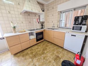 een keuken met houten kasten en een witte magnetron bij Dias de sol in Fuzeta