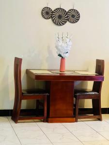 una mesa con dos sillas y un jarrón de flores. en Zuri home 2, en Kampala 5 fotos más