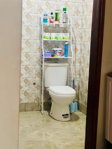 Baño con aseo y estante encima en Zuri home 2, en Kampala