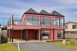 ein rotes Haus mit einem schwarzen Dach in der Unterkunft Amazing Views in Surf Beach