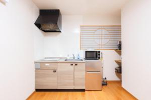 a small kitchen with a sink and a refrigerator at Just a short walk 心斎橋 Glico Sign 1min 道頓堀30-second 黒門市場 難波駅 Dotonbori Guesthouse 松の阁 in Osaka