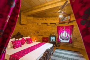 um quarto com uma cama num quarto com cortinas vermelhas em Hotel Rajmandir em Jaisalmer
