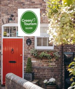 a red door on a brick house with a green tourism silver sign at Ironbridge View Townhouse WINNER 2025 UK MOST PICTURESQUE SELF-CATERING HOLIDAY HOME & WINNER SELF-CATERING ACCOMMODATION OF THE YEAR 2025 in Ironbridge