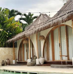 a building with a straw roof and a swimming pool at Lahima Cabanas in Dickwella