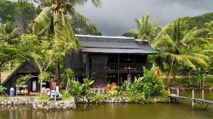 a house on the water with palm trees at Lego Lego Bulubarakka homestay and cafe in Kasijala