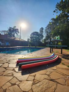 a row of surfboards laying on the ground next to a pool at Refúgio com Piscina, Churrasco e Lazer no Campo in Sumaré