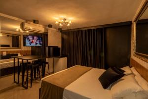 a bedroom with a bed and a table and a kitchen at Hotel Motel Paradiso - Carazinho-RS in Caràzinho