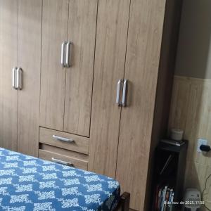 a bedroom with wooden cabinets and a bed with a blue blanket at Apartamento Embaúbas in São José
