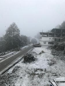 a road with snow on the ground next to a building at Shenga Homestay in Ravangla