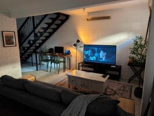 ein Wohnzimmer mit Sofa und Flachbildfernseher in der Unterkunft Peaceful, Modern, LowToxic, Bfast included in Brisbane