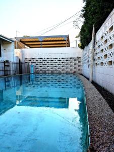 ein Pool mit blauem Wasser neben einer weißen Wand in der Unterkunft Peaceful, Modern, LowToxic, Bfast included in Brisbane