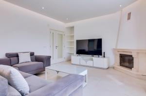 a living room with a couch and a tv and a fireplace at Casa Nuria com 4 quartos, piscina e churrasco em Vale do Lobo in Almancil