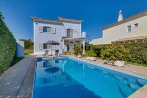 a villa with a swimming pool in front of a house at Casa Nuria com 4 quartos, piscina e churrasco em Vale do Lobo in Almancil