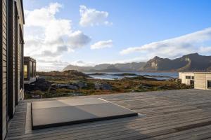 a balcony with a view of the water and mountains at Serene cabin in Lofoten with sauna in Storøya