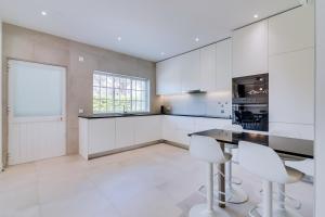 a kitchen with white cabinets and a table and chairs at Casa Nuria com 4 quartos, piscina e churrasco em Vale do Lobo in Almancil