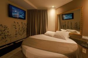 a hotel room with a bed and a mirror at Hotel Motel Paradiso - Carazinho-RS in Caràzinho +12 photos