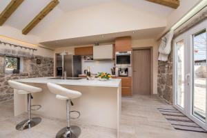 a kitchen with a large white island with stools at Villa Didova kuca ZadarVillas in Podlug +26 photos