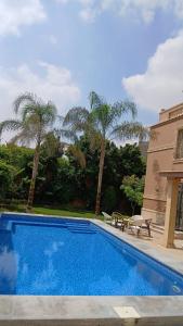 a swimming pool next to a building with palm trees at Royal Mansion with private pool in sheikh zayed Compound families in Sheikh Zayed