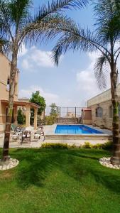 a house with a swimming pool and two palm trees at Royal Mansion with private pool in sheikh zayed Compound families in Sheikh Zayed
