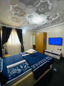 イバダンにあるCozy 4-Bedroom Home in Ibadanの大きなベッドと薄型テレビのある寝室