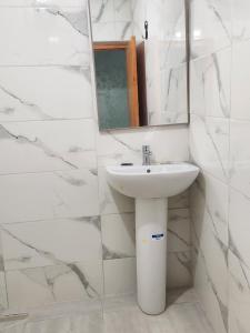 a white bathroom with a sink and a mirror at La Rose De Sable in Aït Ben Haddou +44 photos