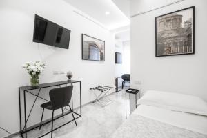 a white bedroom with a bed and a tv on the wall at Talìa Rooms and Gallery in Messina