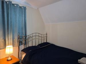a bedroom with a bed with blue sheets and a lamp at Guest Room in Colchester Hythe in Hythe