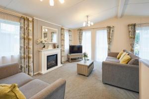 Una sala de estar con dos sofás y un televisor. en Woodpecker Lodge with Hot Tub, en York