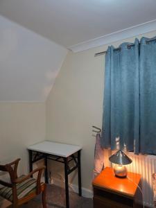 a bedroom with a table and a bed and a table with a chair at Charming Colchester Room with Garden Views in Hythe