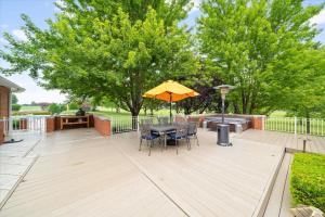 eine Terrasse mit einem Tisch, einem Sonnenschirm und einem Grill in der Unterkunft 2BR Guesthouse Near Lakes with BBQ & Hot Tub in Blue Springs