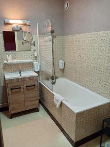 a bathroom with a bath tub and a sink at Hôtel Le Lyon Vert Commentry in Commentry