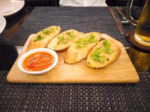 a wooden cutting board with four slices of bread with sauce at An Peaceful Homestay in Cat Ba