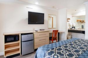 una camera d'albergo con un letto e una TV a schermo piatto di Budget Inn Corcoran Near Tulare CA 43 a Corcoran