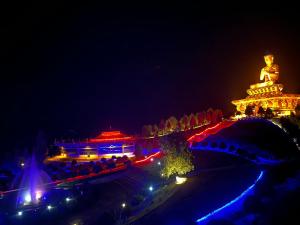 a lit up city at night with a large statue at Shenga Homestay in Ravangla +20 photos