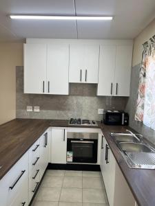 a kitchen with white cabinets and a sink at 101 Maia in Gqeberha